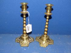 A pair of 19th century cast brass Arts and Crafts religious candlesticks with graduated bobbin stem,