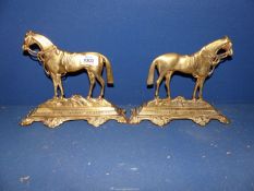 A pair of brass door stops in the form of horses.