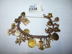 A 9ct gold charm bracelet with heart locket fastenings with 9ct gold yellow gold charms including