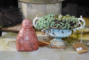 A cast iron planter and a glazed Buddha.