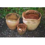 A set of three wavy edged terracotta pots.