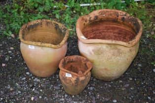 A set of three wavy edged terracotta pots.