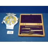 A drawing set in wooden box and an 'AA' badge.