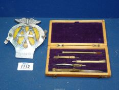 A drawing set in wooden box and an 'AA' badge.