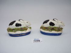 A pair of Staffordshire Rabbits nestled in stylized grass and flowers on royal blue bases,