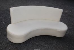 A stylish curved Reception Seat/Sofa upholstered in cream and standing on five tapering turned legs,