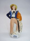 A Staffordshire figure of a sailor with a knapsack on a pole beside him, 7 1/2'' tall.