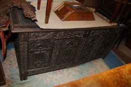 A dark carved Oak four panel Coffer, the panels having heraldic shields and arches,