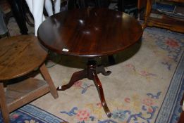 A Mahogany and other woods snap-top circular Table standing on a turned pillar with three elegant