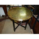 A large brass Benares table on a wooden stand.