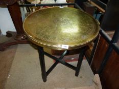 A large brass Benares table on a wooden stand.