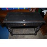 A dark Oak side Table standing on turned and carved legs united by carved and fretwork detailed