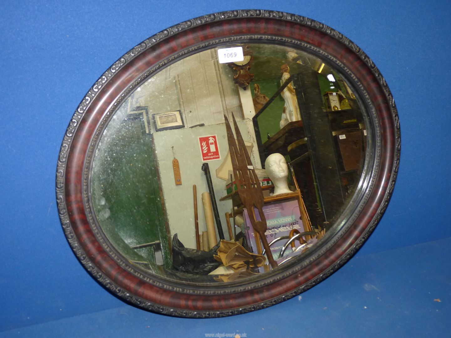 An oval bevelled wall mirror in a dark wood frame.