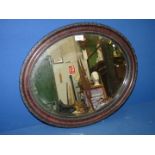 An oval bevelled wall mirror in a dark wood frame.