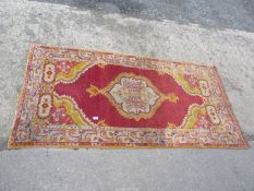 A red, gold and pale blue bordered and patterned Rug in stylised floral motifs, 39 1/2" x 78".