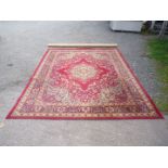 A large red ground, border pattern Rug in blues and cream with central lozenges by Grosvenor Wilton,