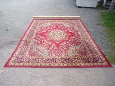 A large red ground, border pattern Rug in blues and cream with central lozenges by Grosvenor Wilton,