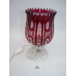 A cut glass table lamp with a clear and cranberry glass shade, 11" tall.