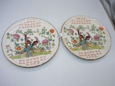 A pair of oriental wall plates with peacocks and blossom decoration.
