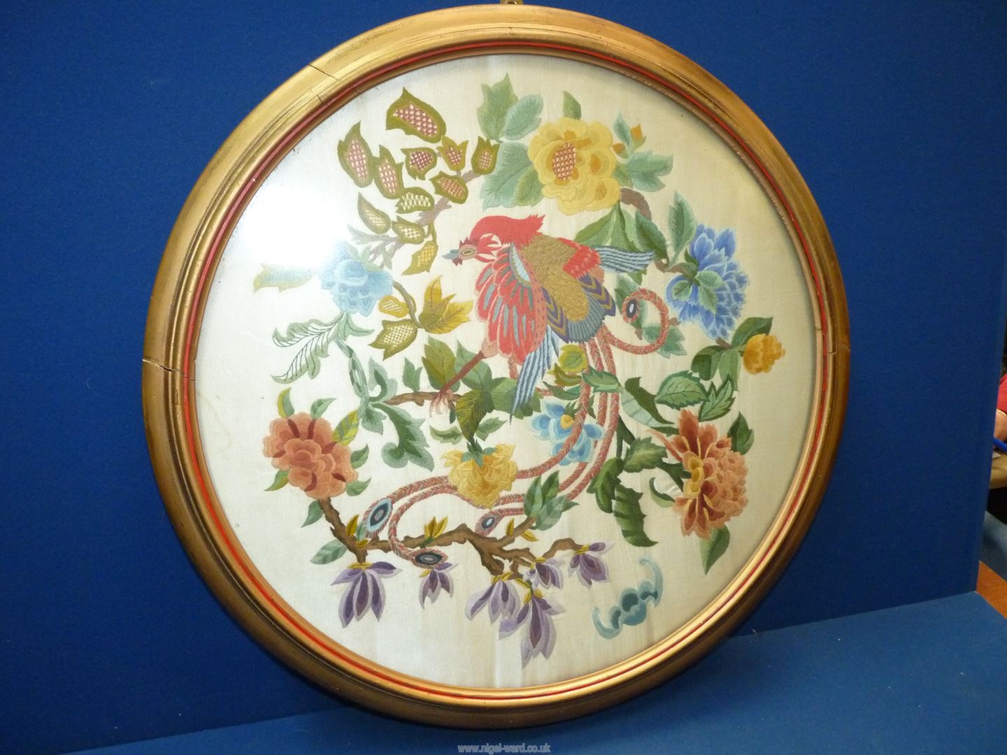 A circular framed Embroidery depicting Chinese style bird of paradise and flowers.