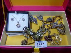 A pink box of costume jewellery including some silver and some marcasite brooches, etc.