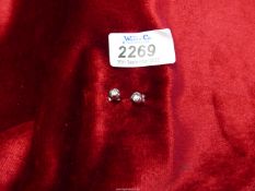 A pair of silver ball stud earrings set with a small diamond.