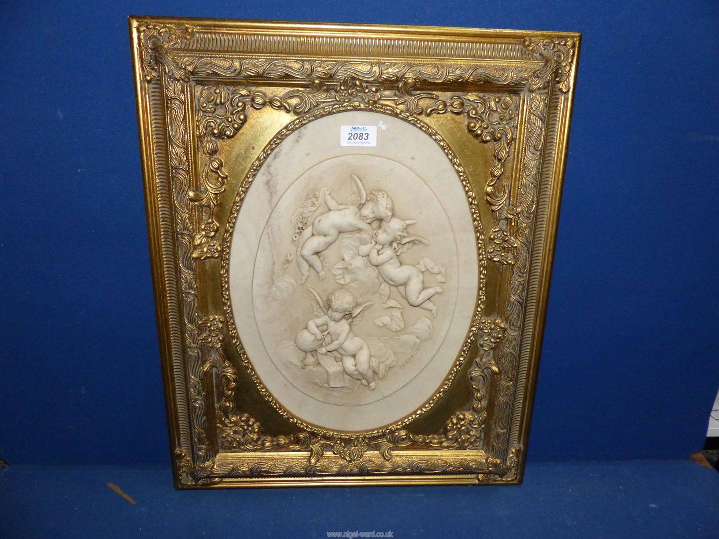 A Madame Leon Bertaux carved oval marble relief Plaque in a gilt frame of three Putti,