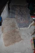 Two rugs - small cream shaggy rug (42" x 26"), plus a cream and blue bordered,