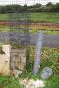 A roll of chicken wire and a roll of barbed wire and a flat pack cage.