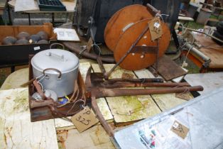 An axe, hacker, pick axe, aluminum pan reel, and old cultivator.