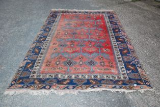 A red/blue bordered, patterned and fringed rug - 116" x 77½" .