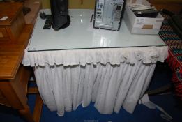 A glass top dressing table with embroidery Anglaise fabric valance.