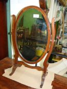 A 19th century oval Mahogany Swing toilet Mirror with bevelled glass on scroll frame,