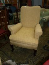 A high back armchair standing on cabriole front legs and upholstered in gold coloured fabric.