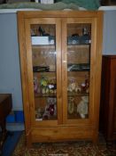 A contemporary light Oak display cabinet having a pair of opposing glazed doors,
