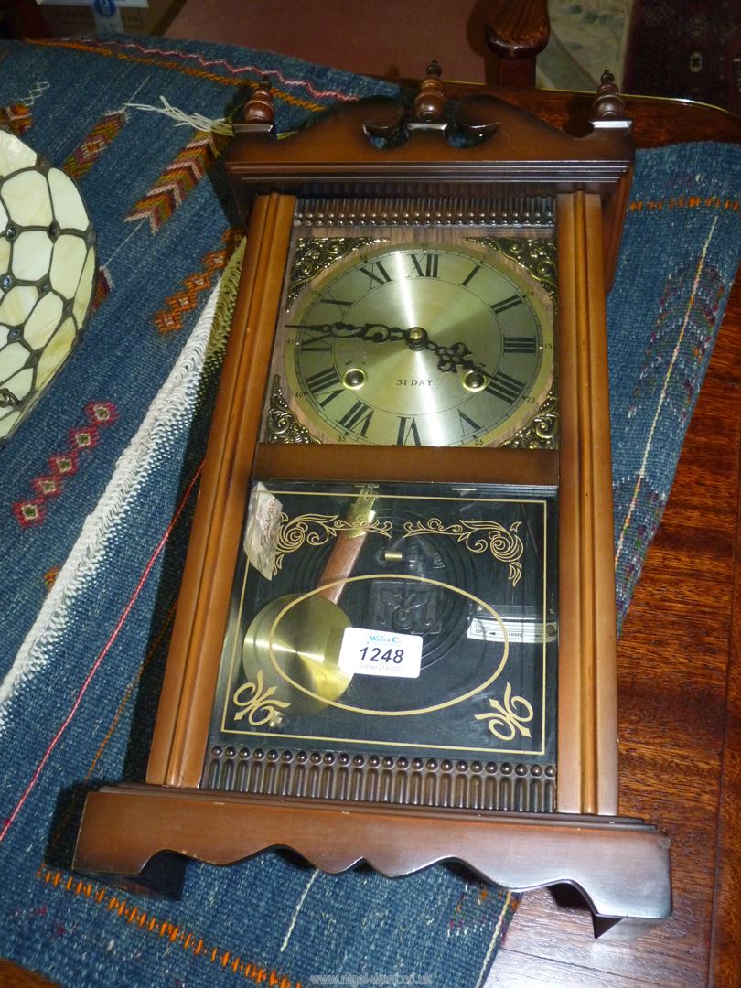 A cased 31 day chiming wall Clock having decorative brass corners around the face,