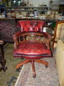 A red buttoned leather upholstered swivel and tilt action office armchair, adjustable for height.