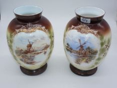 A pair of white glass vases with painted scenes of windmills on brown and green ground,