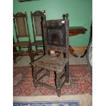 A rustic dark-wood hall chair for restoration having carved details to the backrest,