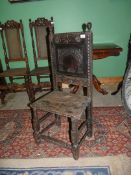 A rustic dark-wood hall chair for restoration having carved details to the backrest,