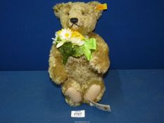 A Steiff Teddy bear holding a bunch of flowers, 13'' tall.