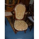 A circa 1900 Mahogany framed nursing chair standing on turned and fluted front legs and upholstered