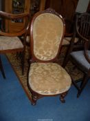 A circa 1900 Mahogany framed nursing chair standing on turned and fluted front legs and upholstered