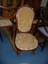 A circa 1900 Mahogany framed nursing chair standing on turned and fluted front legs and upholstered