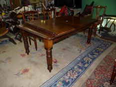 An Edwardian wind-out Mahogany dining table standing on turned and reeded legs,
