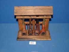 An oak four bay Pipe Rack, fashioned as a roofed lych gate holding three briar pipes, etc.