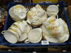 A bone china tea set with pink and yellow floral design including milk jugs and sugar bowls.