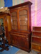 A circa 1900 Mahogany bookcase on cupboard having a full width frieze drawer the opposing arched