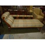 An Edwardian Oak framed chaise longue standing on turned legs and with foliage carved/fret-worked