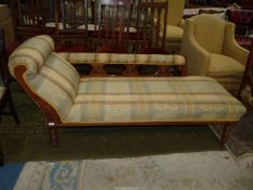An Edwardian Oak framed chaise longue standing on turned legs and with foliage carved/fret-worked